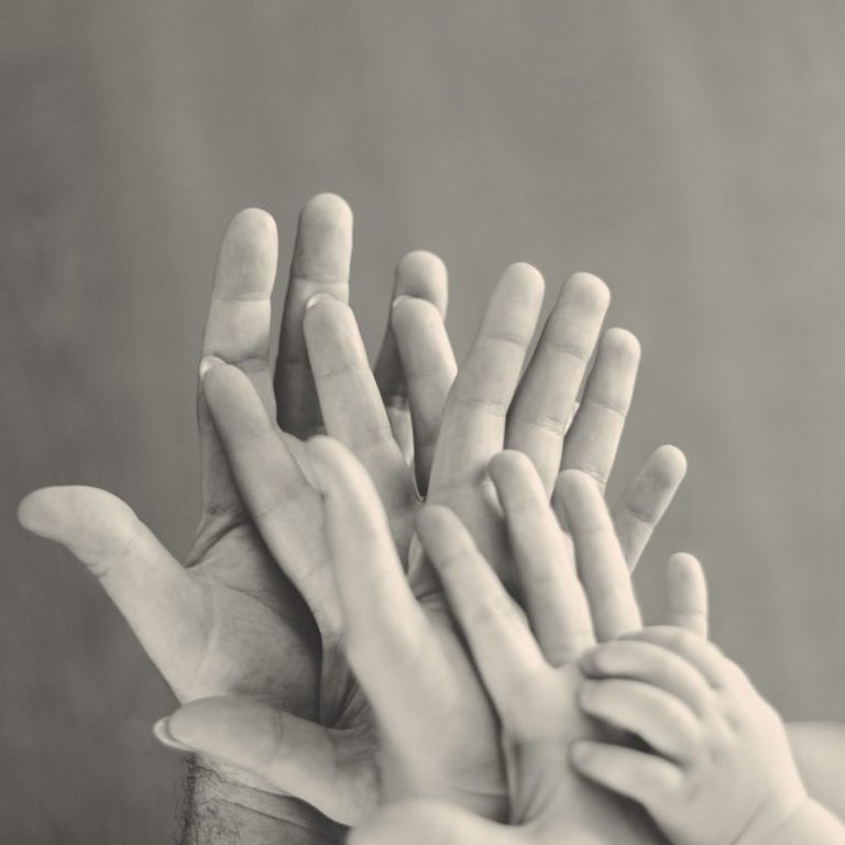 Verschiedene Hände in unterschiedlichen Größen, die übereinander gestapelt sind.