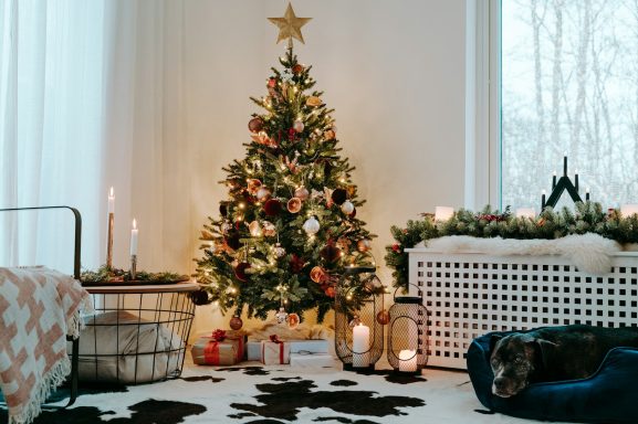 Ein festlich geschmückter Weihnachtsbaum mit Dekorationen und Kerzen in einem stimmungsvollen Raum.