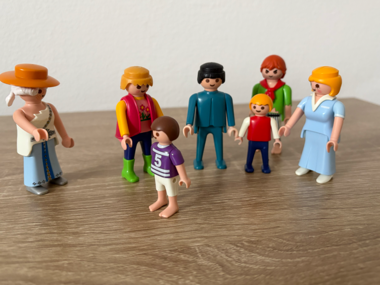 Eine Gruppe von Playmobil-Figuren in verschiedenen Outfits auf einem Holztisch.
