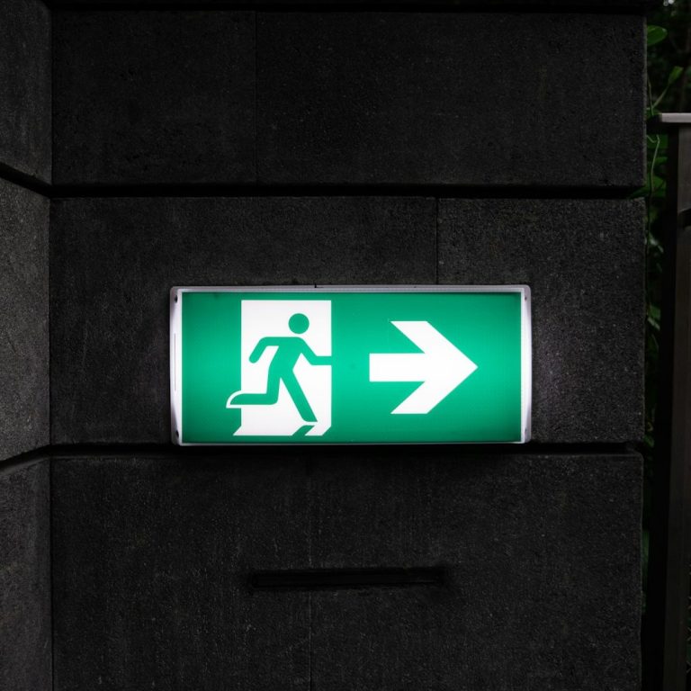 Was tun in seelischen Notfällen? Grünes Notausgangsschild mit nach rechts gerichteter Pfeil- und Fluchtwegsymbolik.